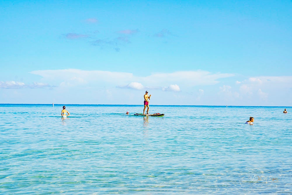 paddleboarding in the ocean around swimmers