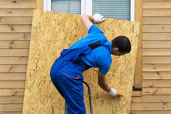 Man removes hurricane window protection from house.