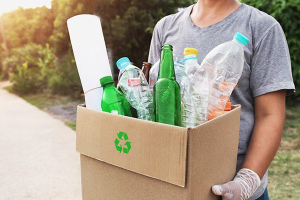 Woman holds box of recycling garbage.